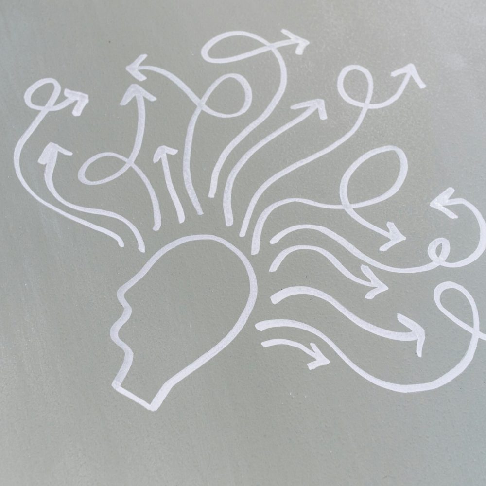 Chalk drawing of a head with swirling arrows represents mental activity and thought process.